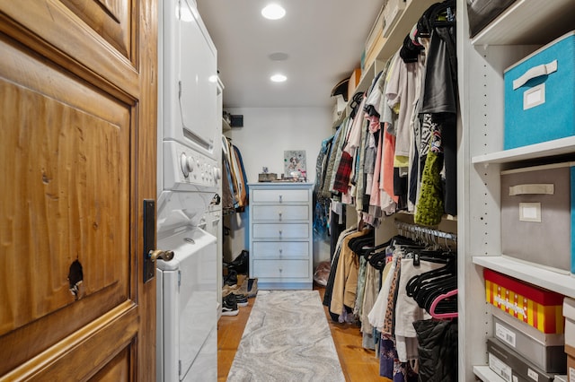 walk in closet featuring light hardwood / wood-style flooring and stacked washer and dryer