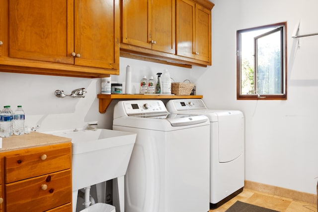 washroom featuring washing machine and dryer, cabinets, and light tile floors