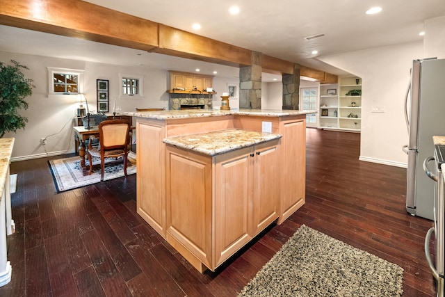 kitchen featuring light stone countertops, tasteful backsplash, stainless steel fridge, a fireplace, and dark hardwood / wood-style flooring