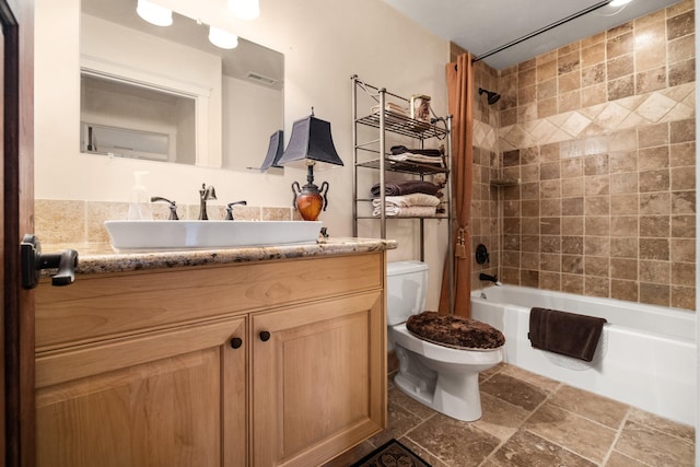 full bathroom with tile floors, vanity, tiled shower / bath combo, and toilet