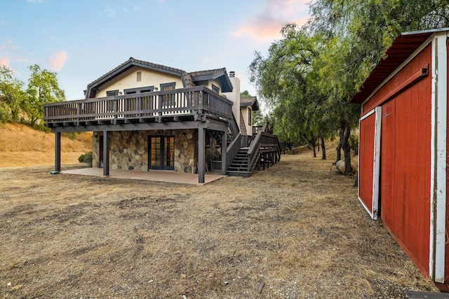 back house at dusk featuring a patio and a wooden deck