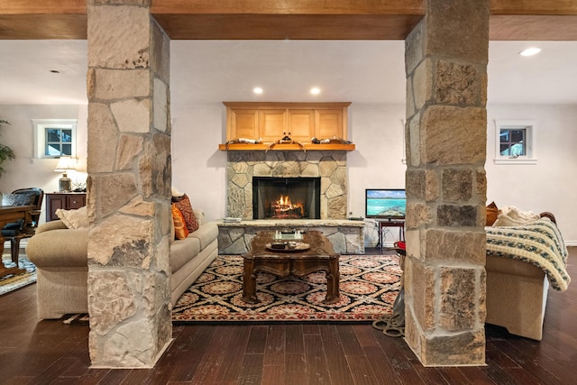 living room featuring dark wood-type flooring, beam ceiling, and a fireplace