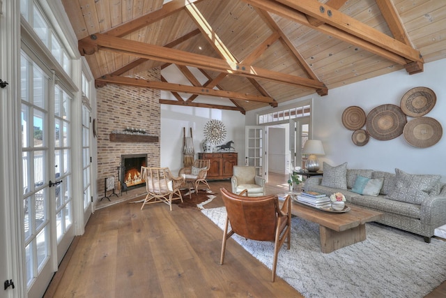 living room with french doors, a brick fireplace, wood-type flooring, and beamed ceiling