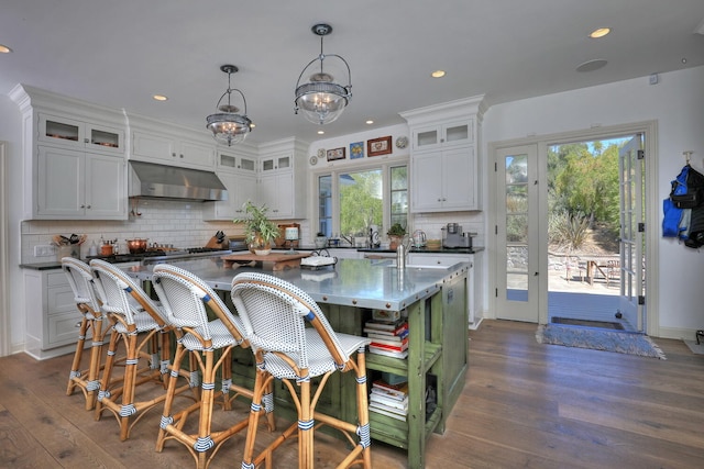 kitchen with hanging light fixtures, white cabinetry, backsplash, a center island, and dark hardwood / wood-style flooring