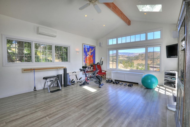 workout area featuring a skylight, a wall mounted AC, ceiling fan, and light hardwood / wood-style flooring