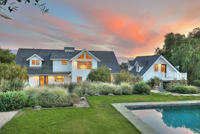 back house at dusk featuring a lawn