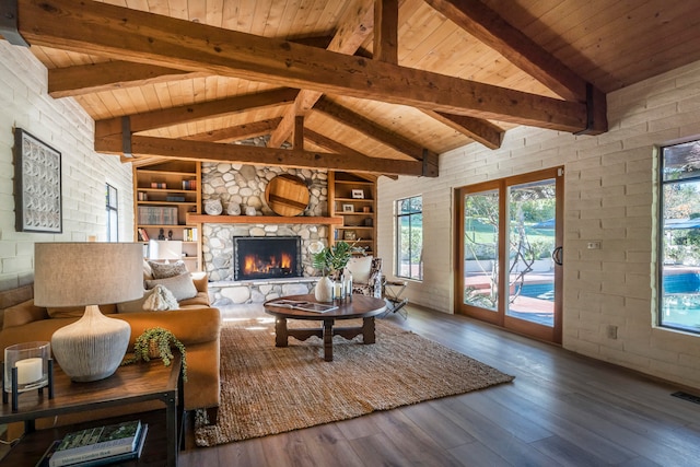 living room featuring built in features, wood ceiling, hardwood / wood-style floors, and a stone fireplace