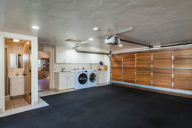 garage with washing machine and clothes dryer, sink, and a garage door opener