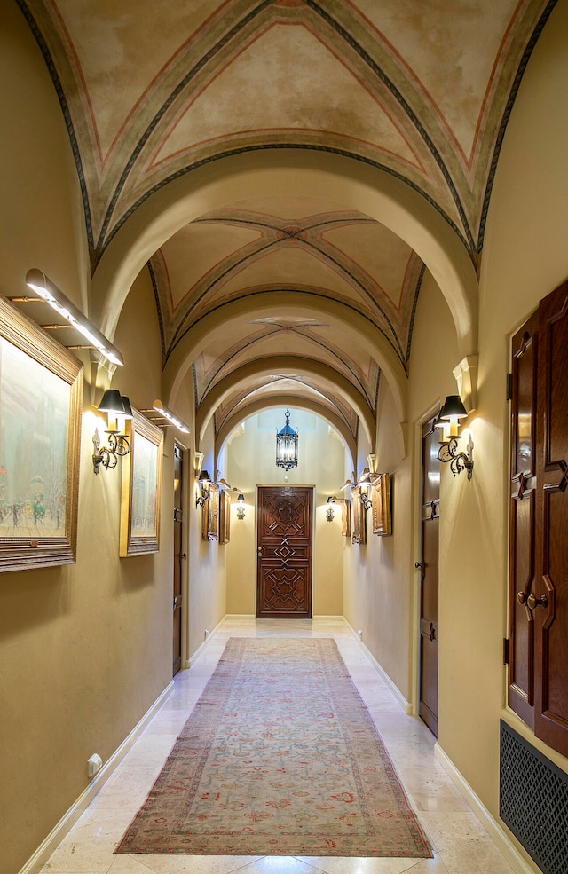 corridor featuring light tile flooring and vaulted ceiling