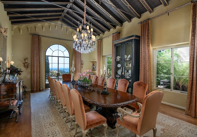 dining room featuring light hardwood / wood-style floors, a notable chandelier, and lofted ceiling with beams