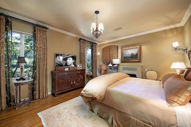 bedroom with ornamental molding, a notable chandelier, and hardwood / wood-style flooring