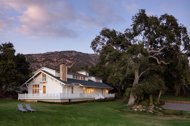 back house at dusk featuring a mountain view and a yard