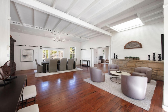 living room with an inviting chandelier, a barn door, beamed ceiling, dark hardwood / wood-style floors, and track lighting