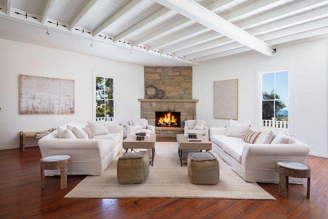 living room featuring a fireplace, beamed ceiling, rail lighting, and wood-type flooring