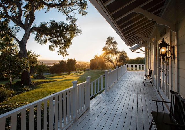 deck at dusk featuring a lawn