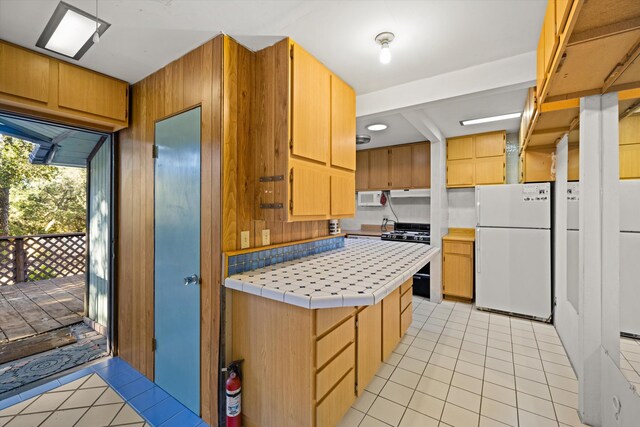 kitchen with light tile floors, range, tile countertops, and white refrigerator