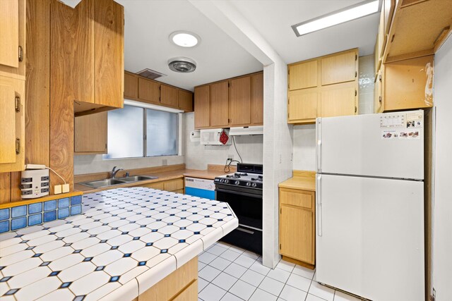 kitchen featuring tile counters, white appliances, sink, and light tile floors