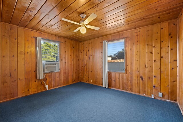 carpeted empty room featuring wood walls, wooden ceiling, and ceiling fan