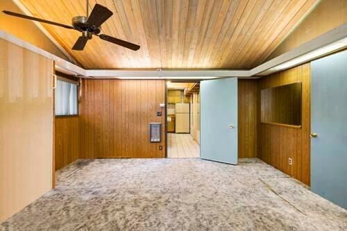 empty room with wooden walls, light colored carpet, ceiling fan, and wood ceiling