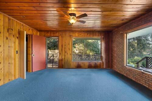 carpeted spare room with wooden ceiling, brick wall, and a wealth of natural light