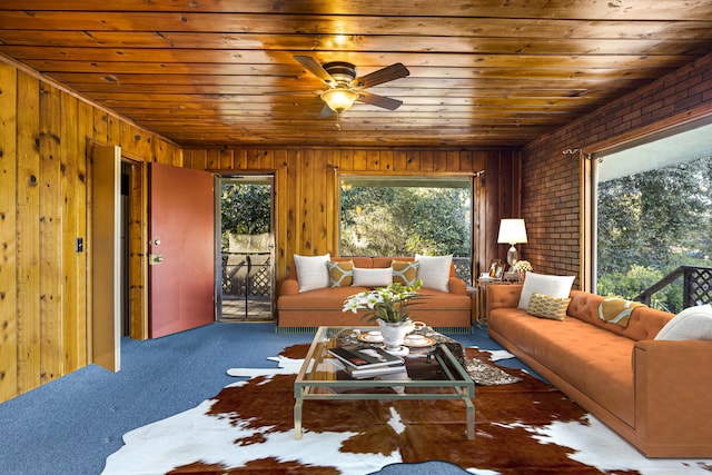 carpeted living room with wooden walls, wood ceiling, brick wall, and ceiling fan