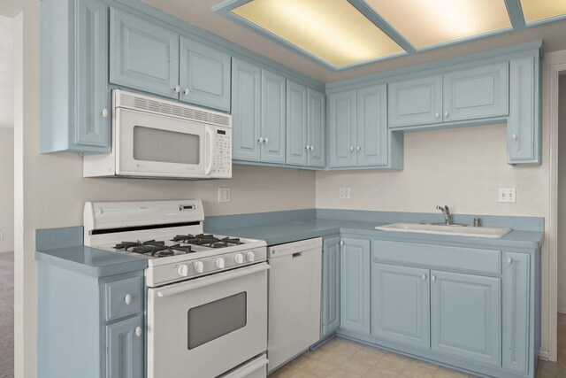 kitchen featuring white appliances, sink, light tile flooring, and blue cabinetry