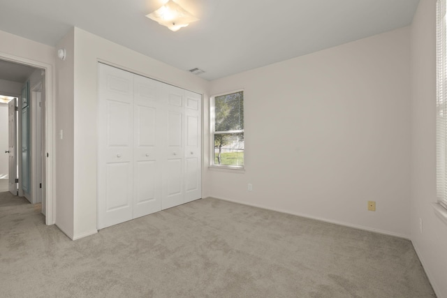 unfurnished bedroom featuring light colored carpet and a closet