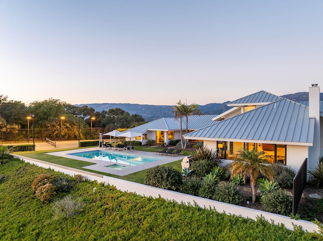 pool at dusk featuring a mountain view and a patio