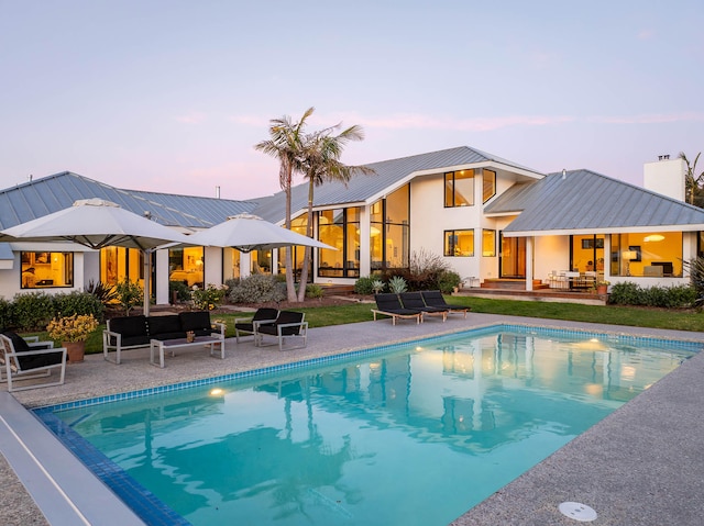 pool at dusk featuring an outdoor hangout area and a patio area