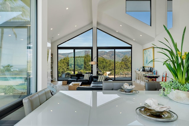 dining area with beam ceiling, a mountain view, and high vaulted ceiling