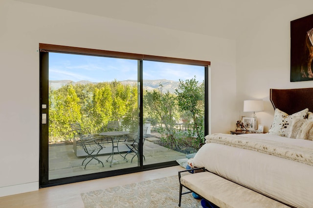 bedroom featuring access to exterior, a mountain view, and light hardwood / wood-style floors