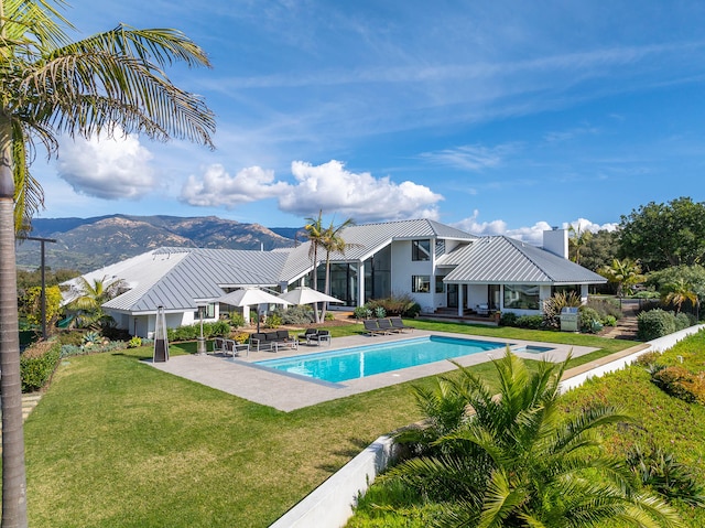 view of swimming pool with a patio, a mountain view, a lawn, and a jacuzzi