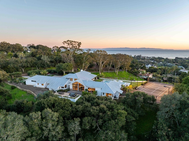 aerial view at dusk featuring a water view