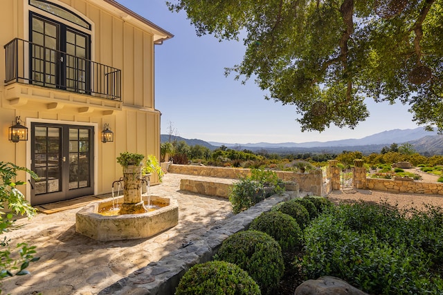 view of terrace featuring french doors, a balcony, and a mountain view