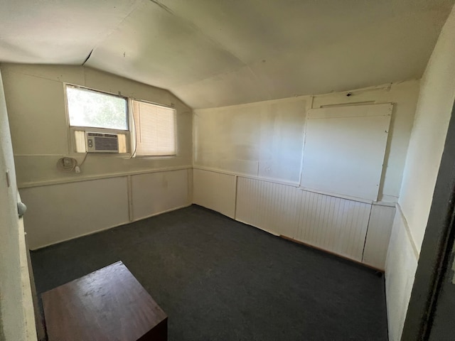 unfurnished room with vaulted ceiling and dark colored carpet