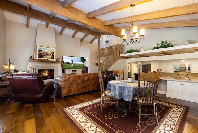 dining area with vaulted ceiling with beams, dark wood-type flooring, and a large fireplace