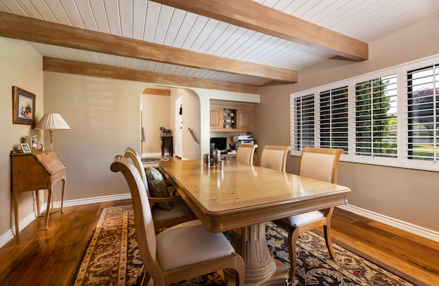 dining room featuring beamed ceiling and dark hardwood / wood-style flooring