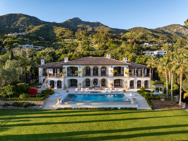 rear view of property with a patio area, a yard, and a mountain view