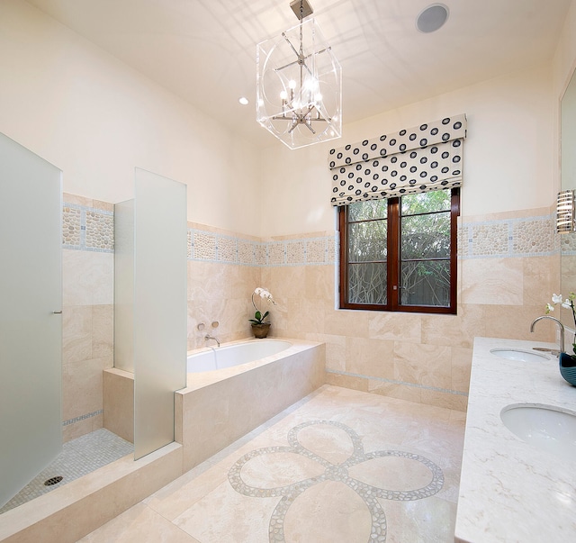 bathroom featuring tile walls, plus walk in shower, a chandelier, and dual sinks