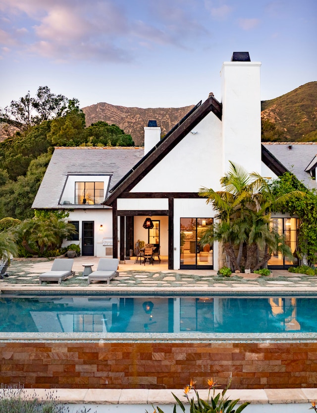 back of property with a mountain view and a patio