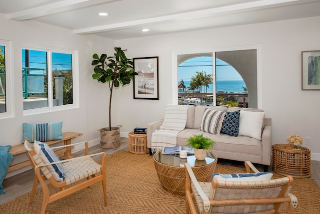 living room featuring beamed ceiling, hardwood / wood-style floors, and a water view