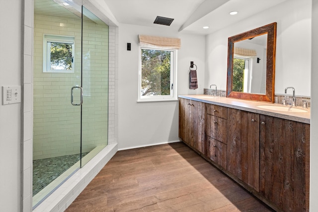 bathroom with an enclosed shower, a wealth of natural light, double sink, and vanity with extensive cabinet space