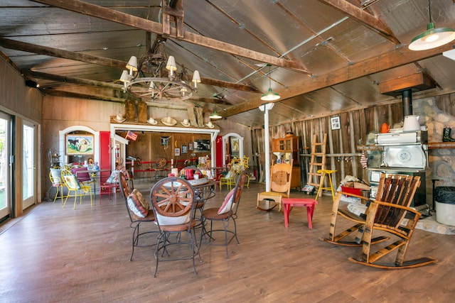 dining room with vaulted ceiling with beams, wooden walls, wood-type flooring, and a chandelier