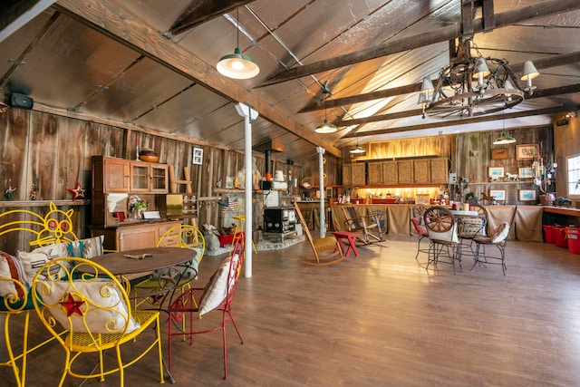 dining area featuring lofted ceiling with beams, wooden walls, and hardwood / wood-style floors