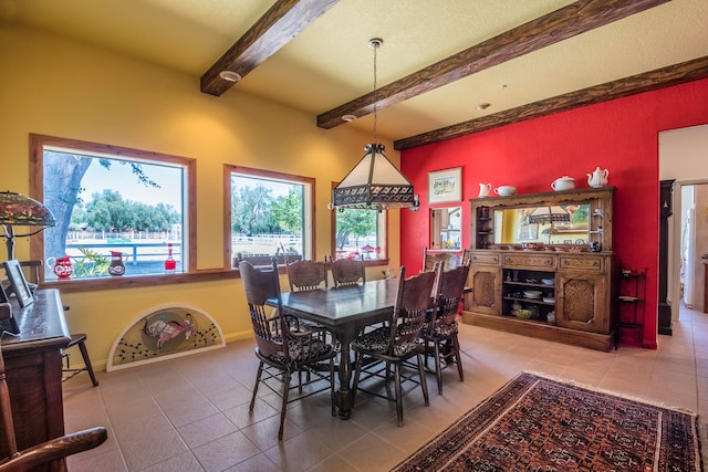 dining area with beamed ceiling and tile floors