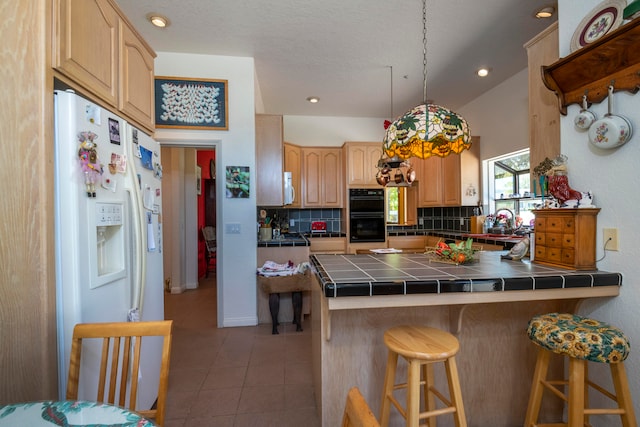 kitchen featuring backsplash, tile flooring, tile countertops, white appliances, and a breakfast bar