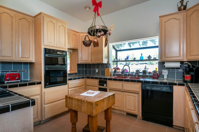 kitchen with backsplash, tile counters, sink, and black appliances