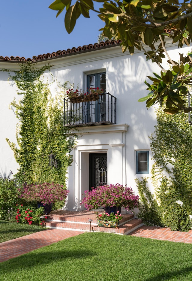 mediterranean / spanish-style house with a front lawn and a balcony