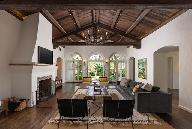 living room with a notable chandelier, a tiled fireplace, wood ceiling, wood-type flooring, and beamed ceiling