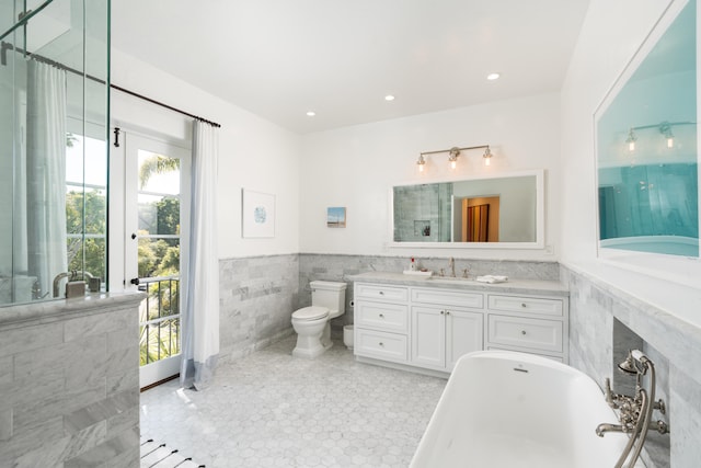 bathroom featuring plenty of natural light, oversized vanity, toilet, and tile walls